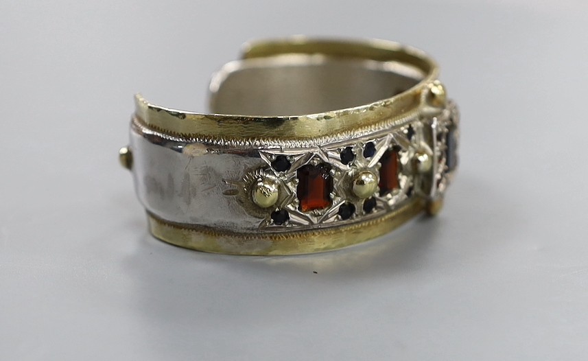 A modern parcel gilt silver and gem set open work bangle by Michael Allen Bolton, London, 1993, interior diameter 56mm, gross weight 67 grams.